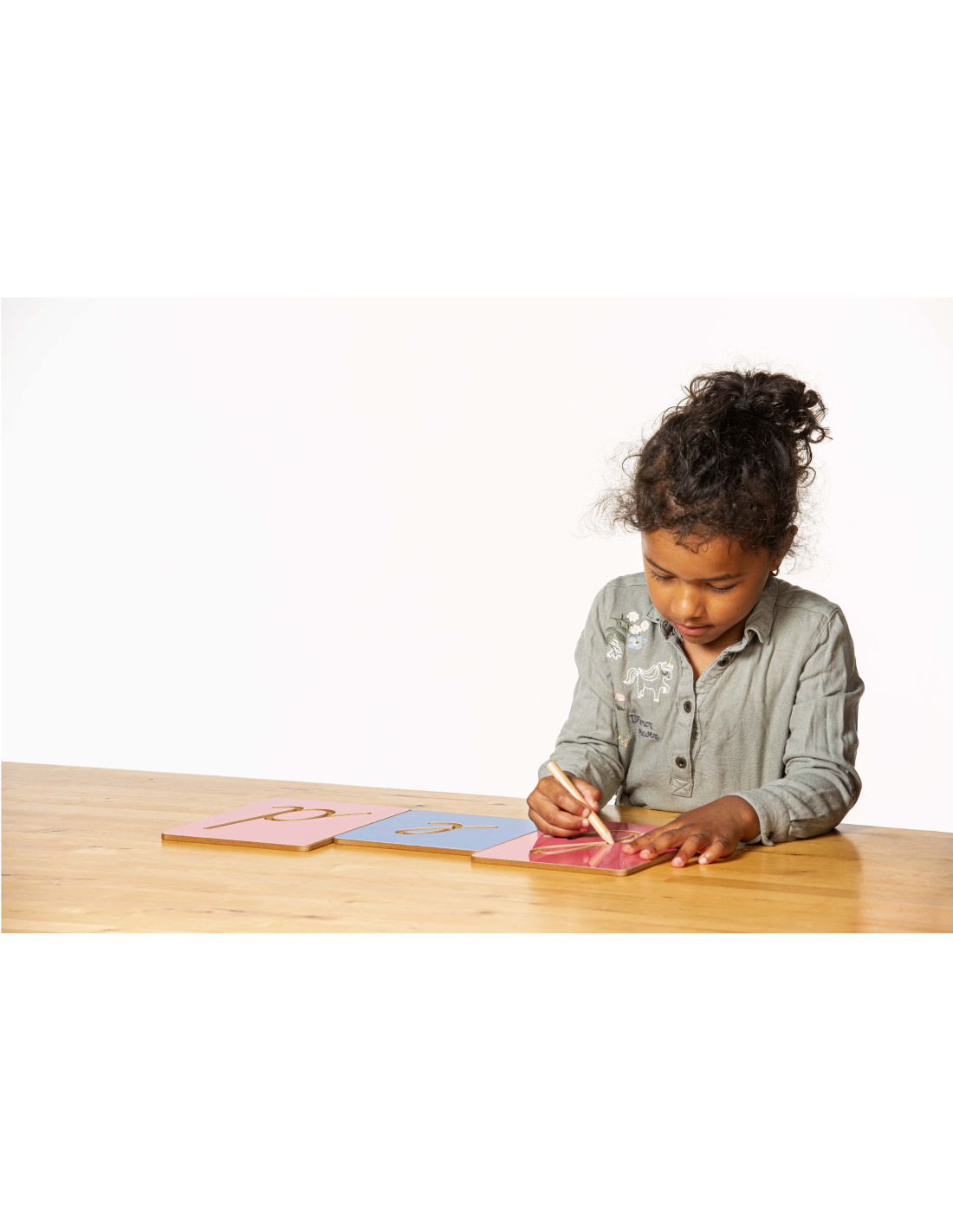 Enfant qui trace des lettres de l'alphabet pour apprendre la graphie des lettres le son et les phonèmes francais