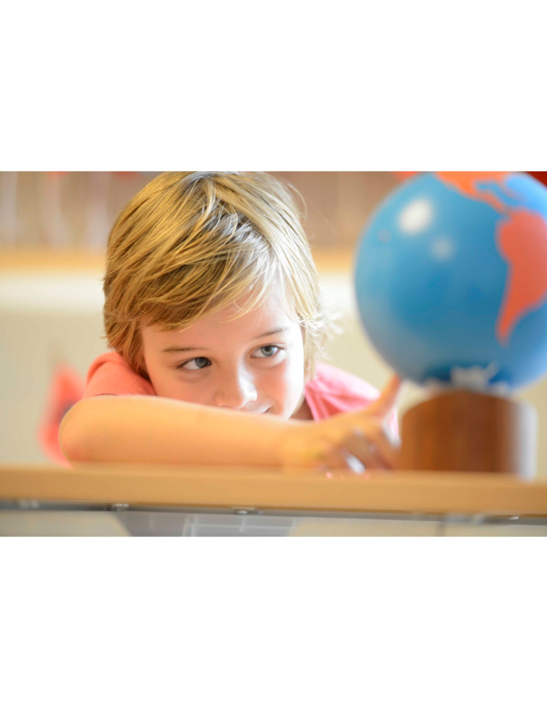 enfant jouant avec un globe terrestre, un matériel de géographie qui permet de découvrir les pays et les cultures du monde entier.