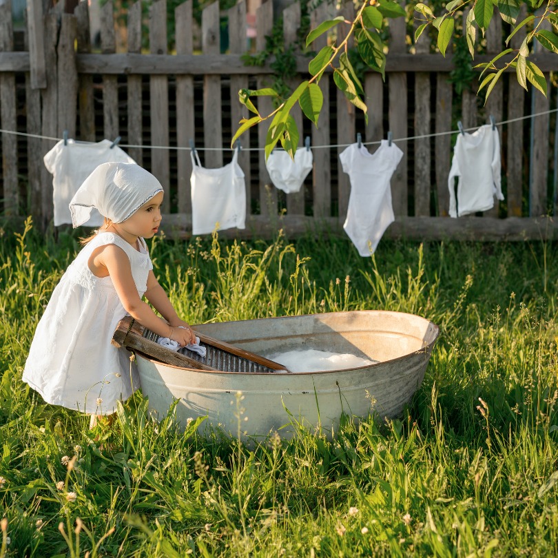 Enfant effectuant le lavage des tissus à l'aide d'une planche à laver et d'un battoir