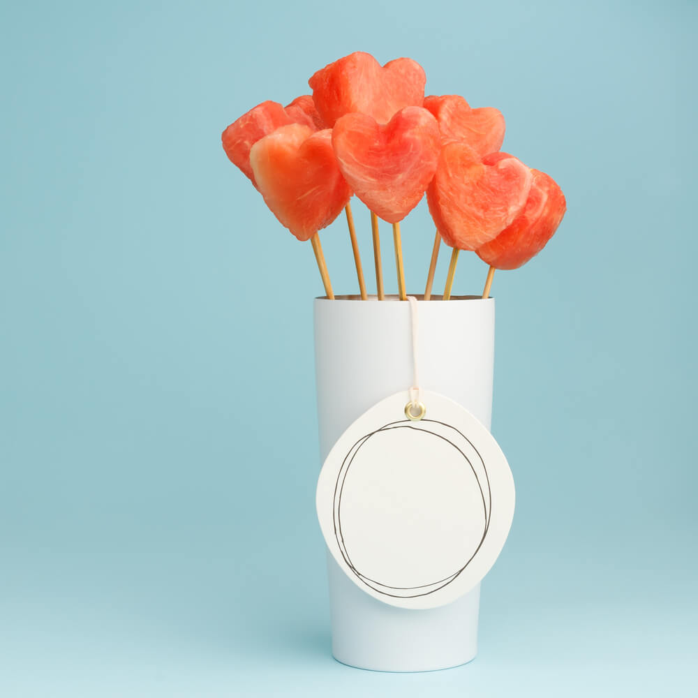 Brochettes de fruits en forme de cœur avec verre de jus d'orange frais