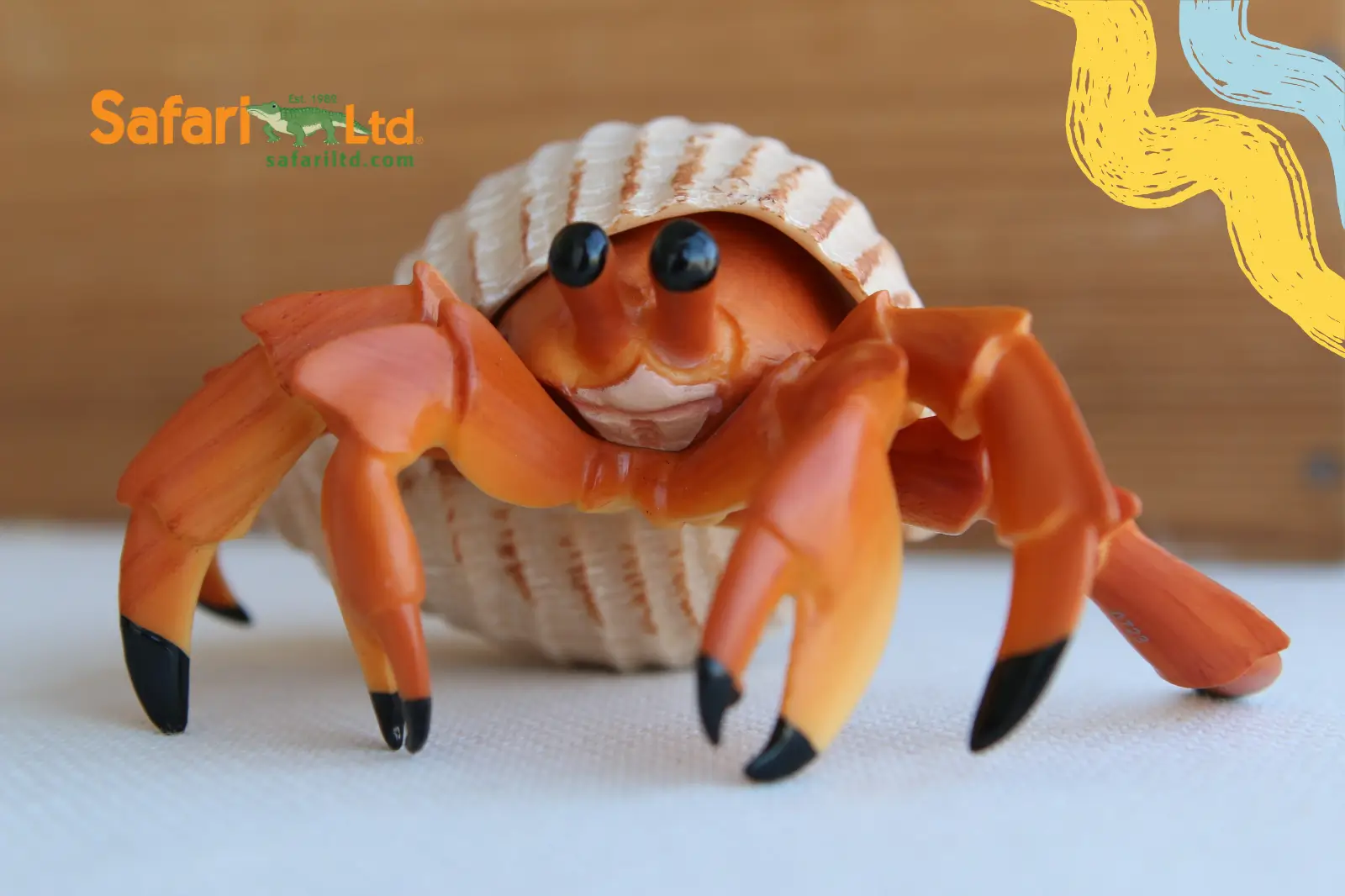 Figurine réaliste de bernard-l'ermite Safari Ltd, pinces orange sortant d'un coquillage, sur fond clair