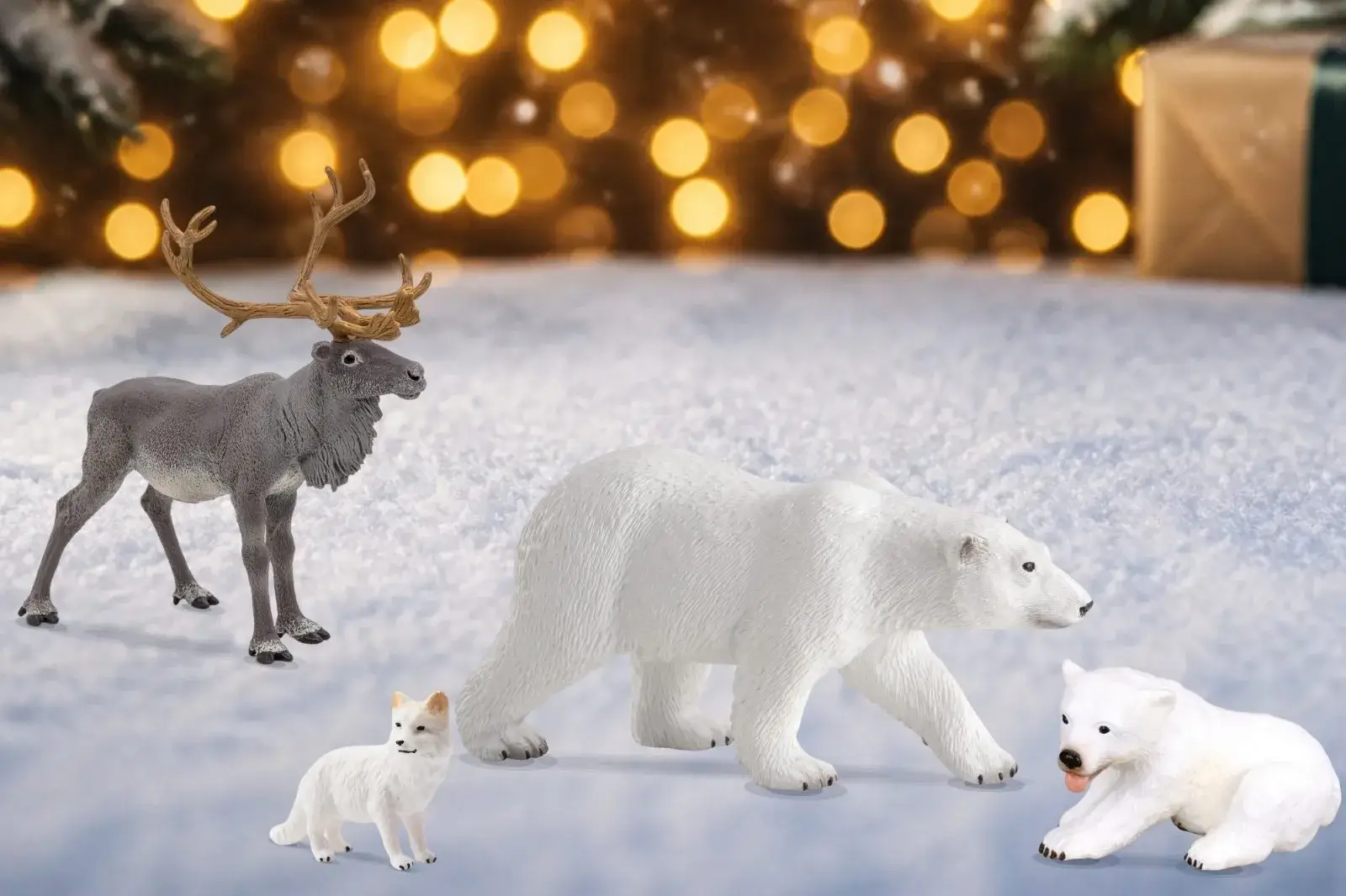 Figurines d'animaux du Grand Nord posées sur la neige devant des guirlandes lumineuses&nbsp;: renne, ours polaire, ourson et renard polaire